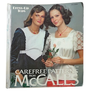 May include: A vintage McCall's sewing pattern book titled "Dress-Up Tops" featuring two women modeling different tops. The cover has the text "Carefree Patterns from McCall's" and the month "December". The women are wearing tops with lace and satin details.
