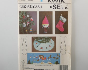 May include: A vintage sewing pattern for Christmas ornaments and a tree skirt. The pattern is called "Kwik Sew" and the pattern number is 828. The pattern includes instructions for making a stocking, a gnome, a Christmas tree, and a tree skirt. The pattern is designed by Kerstin Martensson.