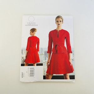Pode incluir: Um padrão de costura com um vestido vermelho com detalhe de laço e casaco a condizer. O padrão está rotulado como "CHADO ralph rucci" e "V1317". O vestido tem decote em V e mangas três quartos. A imagem mostra uma mulher a usar o vestido.
