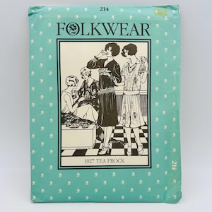 May include: A Folkwear 214 1927 Tea Frock sewing pattern envelope in light blue with a repeating white floral pattern. The front features a black and white illustration of four people in 1920s attire, with the text Folkwear and 1927 Tea Frock.