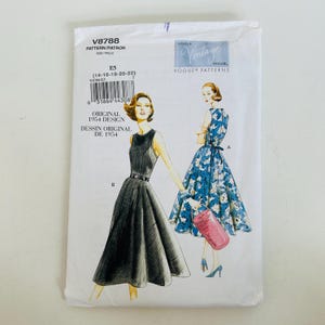 Könnte beinhalten: Ein Vogue Vintage Model Schnittmusterumschlag V8788 für ein Design von 1954. Der weiße Papierumschlag zeigt Illustrationen von zwei Kleidern: eines in einfarbigem Schwarz und eines in Blau mit weißem Blumenmuster, beide mit weitem Rock und Gürtel.
