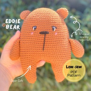 Puede incluir: Un oso de crochet marrón con el texto "Eddie Bear". El oso tiene orejas pequeñas, una nariz negra y mejillas rosas. La imagen también incluye el texto "Super Cute", "Minimal sewing required" y "Low-sew PDF Pattern".