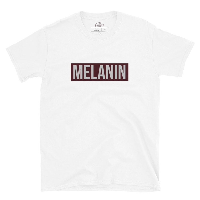 May include: White t-shirt with a maroon rectangle that says "MELANIN" in white letters.