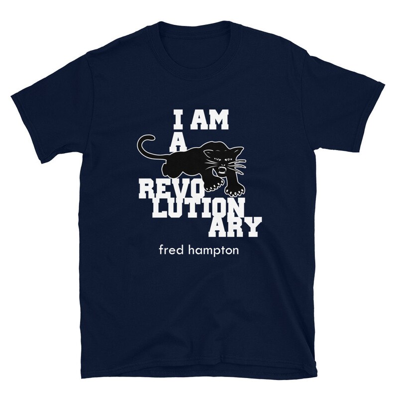 May include: A navy blue t-shirt with white text that reads "I am a revolutionary" and a black panther graphic. The text "fred hampton" is printed below the graphic.