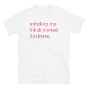 May include: White t-shirt with the text "minding my black owned business." printed in pink.