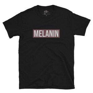 May include: Black t-shirt with a brown rectangle that says "MELANIN" in white letters.