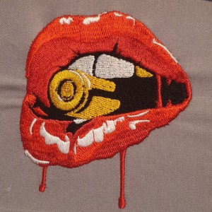 May include: Embroidered patch of a red, open mouth with a gold and black bullet inside. The mouth is dripping with red, resembling blood.