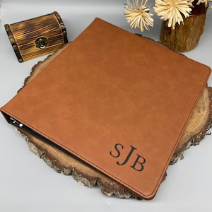 May include: A brown leather binder with a black zipper and the initials "SJB" embossed in black.