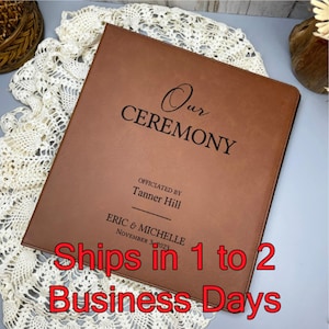 May include: A brown leather-bound album with the text "Our Ceremony" embossed in black. The album is personalized with the names "Eric & Michelle" and the date "November 2023".