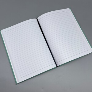 May include: A blank, lined notebook with a light green cover. The notebook is open to a blank page.