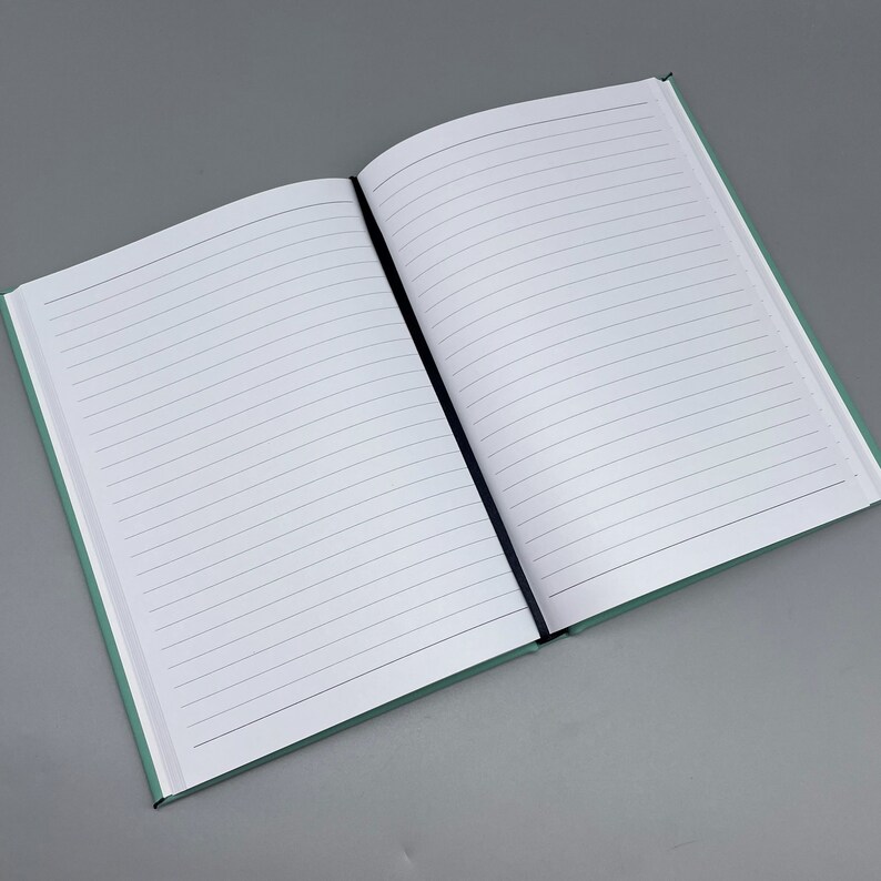 May include: A blank, lined notebook with a light green cover. The notebook is open to a blank page.