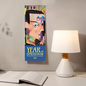 May include: A vertical calendar featuring an expressionist artwork of a face with glasses and a house in the background. The calendar has the text "YEAR IN EXPRESSIONISM" and "2026". A white lamp with a wooden base sits on a white table.