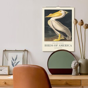 Peut inclure: Un calendrier mural avec une illustration vintage d'un p&eacute;lican tir&eacute;e de "Birds of America" de John James Audubon. Le calendrier a un fond cr&egrave;me avec le texte "Birds of America" et "Calendar 2023."