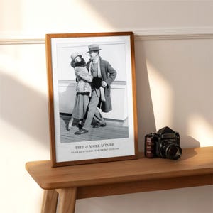 Puede incluir: Una fotografía enmarcada en blanco y negro de Fred y Adele Astaire bailando, con el texto "FRED & ADELE ASTAIRE" y "GOLDEN AGE OF SILENCE - BAIN PORTRAIT COLLECTION" impreso en la parte inferior de la lámina en un marco de madera.