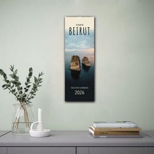 May include: A vertical calendar featuring a photograph of two rocky islands in the water. The calendar is titled "A Year in Beirut" and "The City of Contrasts" with the year 2026.