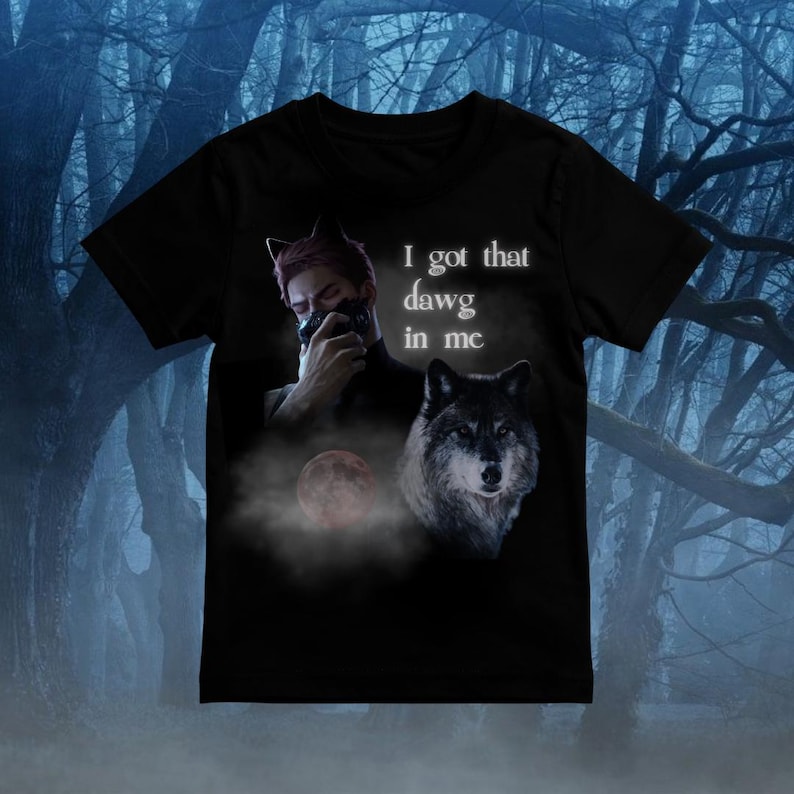 Puede incluir: Una camiseta negra de manga corta con un estampado gr&aacute;fico de una persona con orejas de gato cubri&eacute;ndose la boca con la mano, una cabeza de lobo, una luna roja y el texto blanco "I got that dawg in me" en la parte delantera.