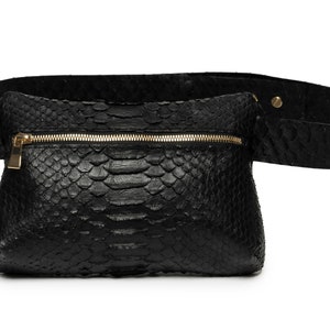 Könnte beinhalten: Eine schwarze Leder-Bauchtasche mit einem goldenen Reißverschluss und einem Schlangenhautmuster.