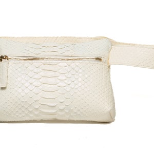 May include: A white leather fanny pack with a zipper closure and a snakeskin pattern.
