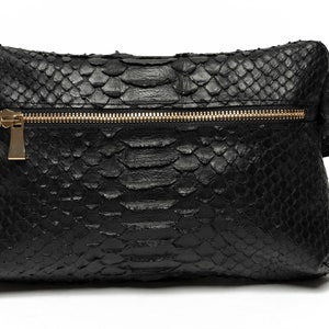 May include: A black snakeskin clutch bag with a gold zipper.