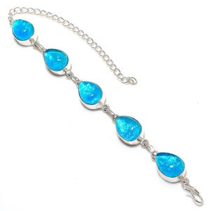 Puede incluir: Una pulsera de plata con piedras preciosas azules brillantes en forma de lágrima. Las piedras están engastadas en biseles individuales de plata y conectadas por pequeños eslabones de plata. La pulsera tiene una extensión de cadena y un cierre de broche.
