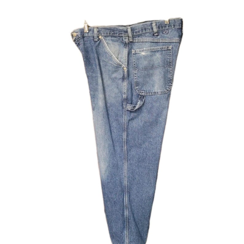 May include: A pair of light blue denim work pants featuring a classic five-pocket design, a metal button closure at the waist, a hammer loop on the side, and visible stitching along the seams with a faded wash finish throughout the fabric.