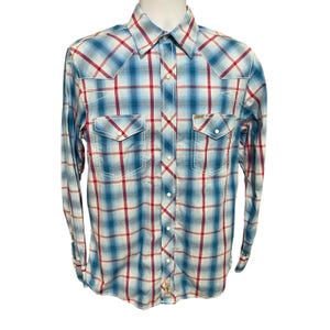 May include: A long-sleeve plaid shirt in shades of blue, red, and white. The shirt features two chest pockets with button closures, a button-down front, and white stitching details. The shirt is displayed on a white mannequin.