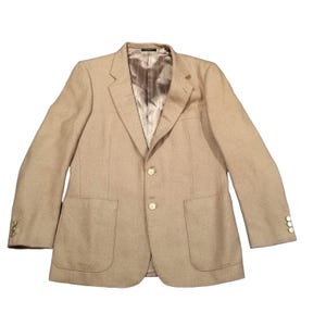 May include: A tan blazer featuring a two-button front closure, two large patch pockets on the lower front, and three buttons on each sleeve cuff. The interior is lined with a light brown fabric featuring a subtle vertical pinstripe pattern.
