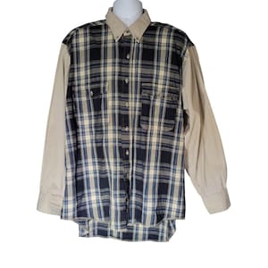 May include: A button-down shirt with a plaid pattern in navy blue, cream, and light blue. The sleeves and collar are a solid tan color. The shirt has two chest pockets and a button-down front.