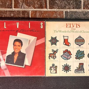 May include: Two vintage Elvis Presley Christmas albums. One album cover is red with a photo of Elvis and the text "Memories of Christmas." The other album cover is beige with Christmas icons and the text "Elvis sings The Wonderful World of Christmas."
