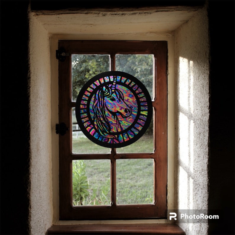May include: A colorful stained glass window with a unicorn design. The unicorn is surrounded by a rainbow of colors and is set against a black background.