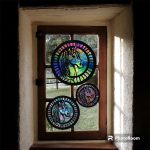 May include: Three iridescent round window hangings with a unicorn design. The hangings are made of stained glass and feature a rainbow color scheme.