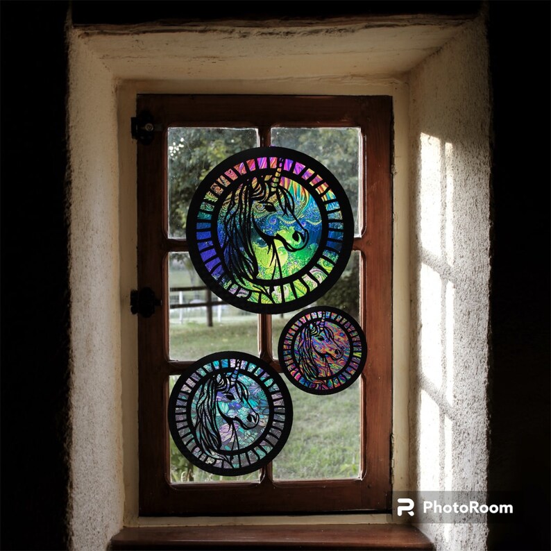 May include: Three iridescent round window hangings with a unicorn design. The hangings are made of stained glass and feature a rainbow color scheme.