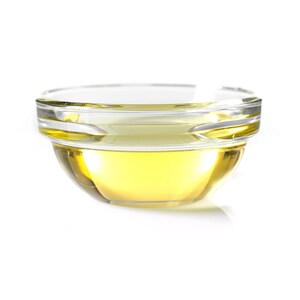 May include: A clear glass bowl filled with a golden yellow liquid, likely oil, on a white background.