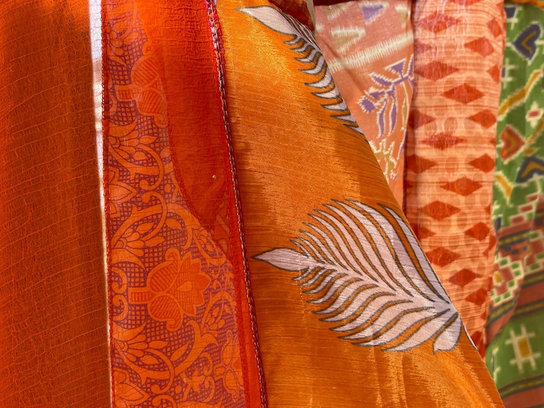 Pode incluir: Close-up de um tecido colorido com uma variedade de padr&otilde;es, incluindo desenhos florais e geom&eacute;tricos. O tecido &eacute; laranja, vermelho, branco e verde.