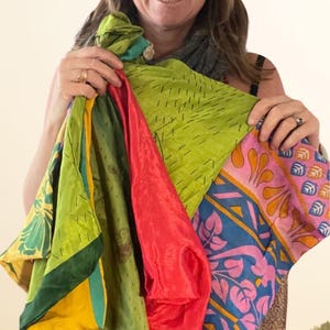 May include: A collection of colorful silk scarves in shades of green, red, pink, and blue. The scarves feature various patterns, including floral and geometric designs. The image shows a variety of textures and colors, creating a vibrant display.