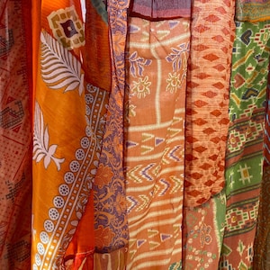 Pode incluir: Um remendo de retalhos de tecido costurados juntos para criar um tecido colorido e texturizado. O tecido &eacute; uma mistura de laranja, vermelho, verde e azul com v&aacute;rios padr&otilde;es.