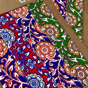 May include: Close-up of colorful paper strips with floral patterns. The strips feature red, blue, and green backgrounds with gold and white floral designs. The text "I'M RECYCLED COTTON PAPER" is visible.