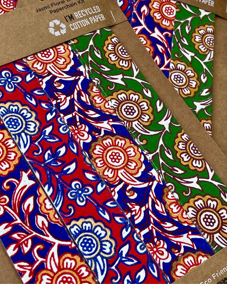 May include: Close-up of colorful paper strips with floral patterns. The strips feature red, blue, and green backgrounds with gold and white floral designs. The text "I'M RECYCLED COTTON PAPER" is visible.