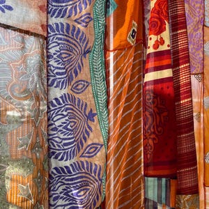 Pode incluir: Uma tape&ccedil;aria colorida de patchwork feita de v&aacute;rios tecidos com padr&otilde;es e texturas diferentes. A tape&ccedil;aria apresenta uma mistura de cores laranja, vermelho, roxo, verde e branco.