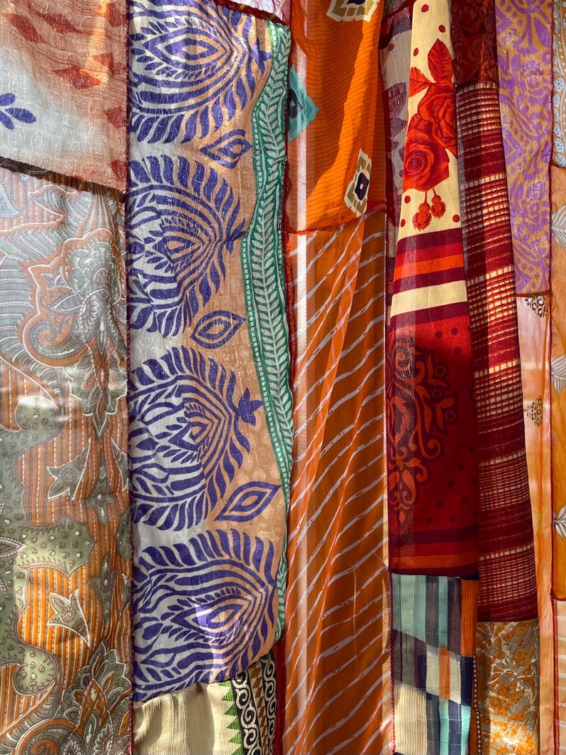 Pode incluir: Uma tape&ccedil;aria colorida de patchwork feita de v&aacute;rios tecidos com padr&otilde;es e texturas diferentes. A tape&ccedil;aria apresenta uma mistura de cores laranja, vermelho, roxo, verde e branco.