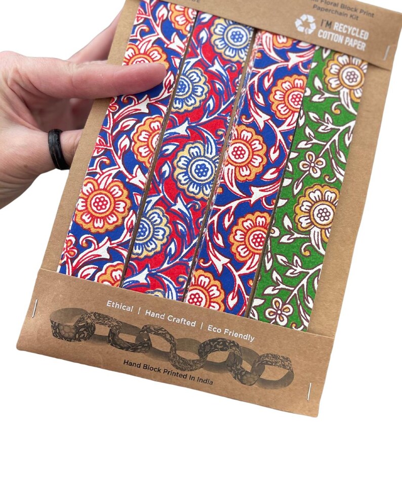 May include: A paperchain kit with four strips of floral block print in red, blue, and green. The kit is made from recycled cotton paper and is hand block printed in India. The packaging reads "Ethical | Hand Crafted | Eco Friendly."