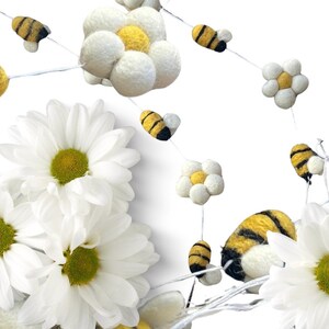 May include: A whimsical garland featuring felted bees and flowers. The bees are yellow and black, while the flowers are white with yellow centers. The garland is set against a white background, creating a cheerful and decorative accent.