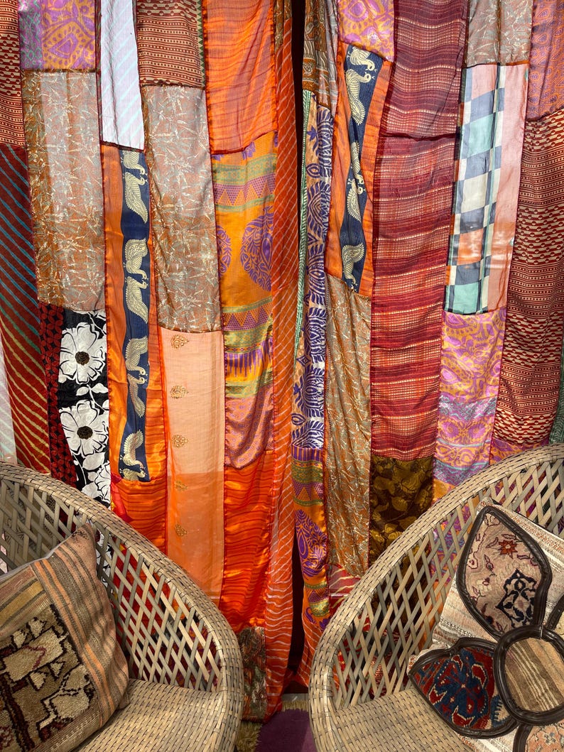 Pode incluir: Duas cadeiras de vime com almofadas estampadas est&atilde;o em frente a uma tape&ccedil;aria colorida feita de muitos tecidos diferentes. A tape&ccedil;aria &eacute; feita de uma variedade de cores, incluindo laranja, vermelho, roxo e verde. A tape&ccedil;aria &eacute; feita de uma variedade de tecidos, incluindo seda, algod&atilde;o e veludo.
