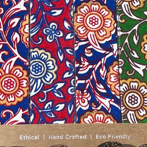 May include: Close-up of four colorful bookmarks with floral patterns. The bookmarks feature red, blue, and green backgrounds with white and gold floral designs. The text "Ethical | Hand Crafted | Eco Friendly" is visible at the bottom.