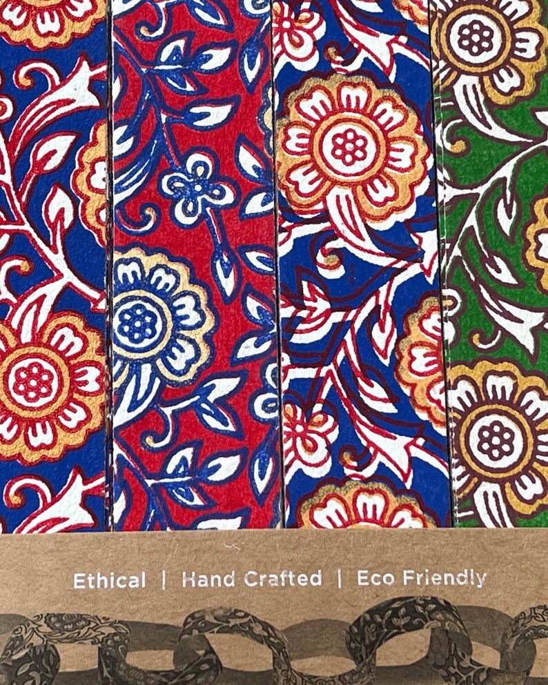 May include: Close-up of four colorful bookmarks with floral patterns. The bookmarks feature red, blue, and green backgrounds with white and gold floral designs. The text "Ethical | Hand Crafted | Eco Friendly" is visible at the bottom.
