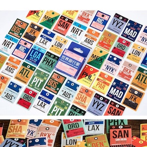 Peut inclure: Un ensemble d'autocollants colorés sur le thème du voyage, avec des codes d'aéroport tels que LAX, JFK et NRT. Les autocollants ont un design rétro et sont de formes et tailles variées, avec une petite boîte d'autocollants.