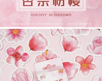 May include: Pink cherry blossom stickers with watercolor designs. The stickers are in various shapes and sizes, with a package of stickers in the center. The text on the package reads "Cherry Blossoms". The background is a soft pink.