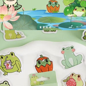 May include: A set of frog-themed stickers featuring various poses and activities, including a frog drinking milk, a frog in a pumpkin, a frog playing a guitar, and a frog holding a flower. The stickers are on a light green background with the text "Xiao Gua's daily life" and "My life's getting better." in English and Chinese.