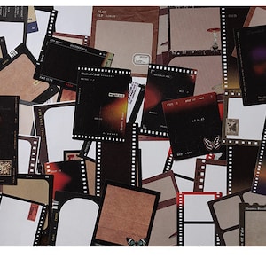 May include: A collection of vintage-style film strip photo frame stickers. The stickers are brown, black, and white with a film strip border and a blank space for a photo. Some of the stickers have text on them, such as "Play Slow" and "Shades of Film".