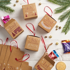 May include: A set of 10 brown cardboard boxes with red ribbon and snowflake designs. Each box has a different number from 1st to 7th December printed on it. The boxes are for a Christmas advent calendar.